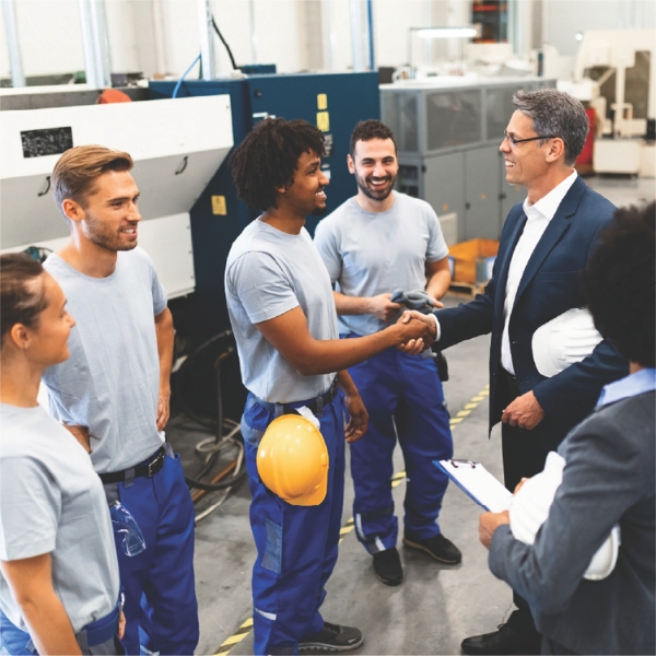 Manager shaking hands with workers on a factory floor.